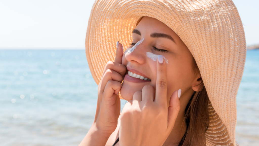 Woman putting sunscreen cream. Wearing a sun cap . At the beach .